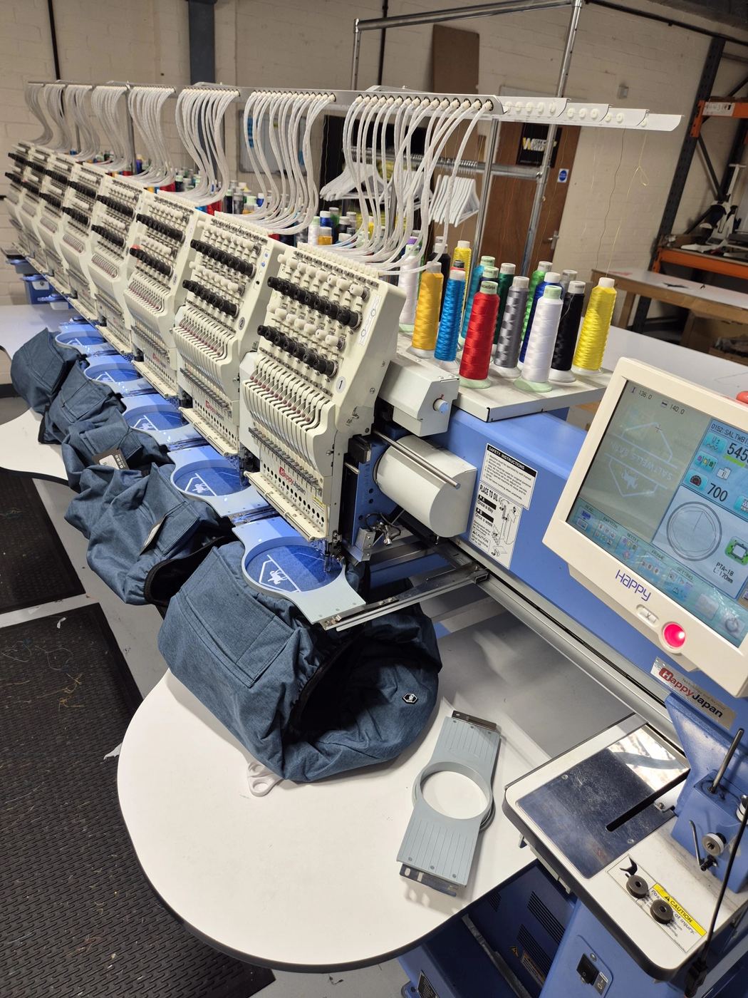 Multi head embroidery machine stitching logos onto bags in our studio
